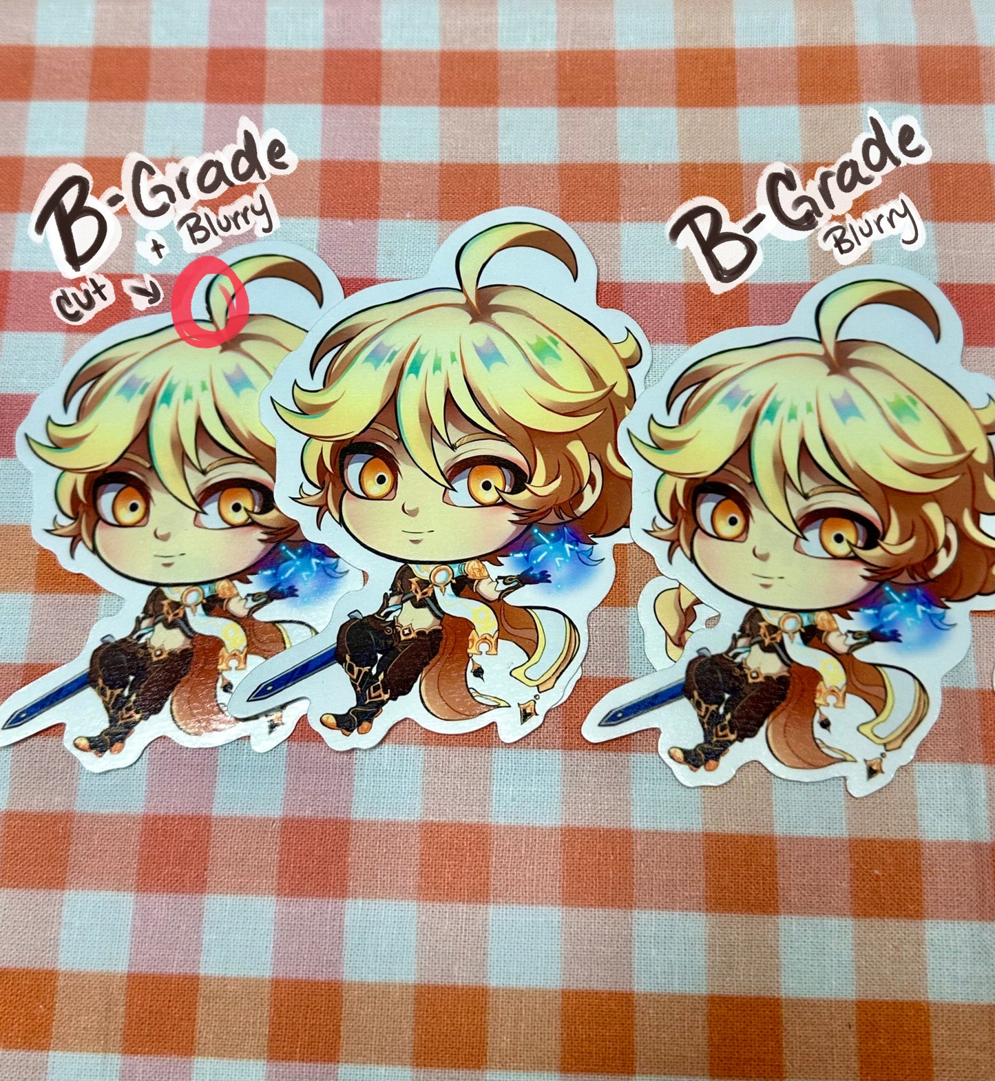 Different versions of B-grade chibi Aether stickers. One with a slight cut and blurry print. The other only blurry print. Both compared to a perfect condition Aether sticker.